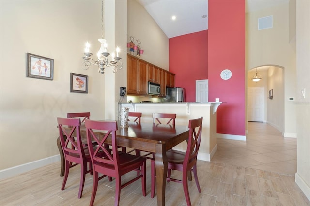 dining area with an inviting chandelier, high vaulted ceiling, and light wood-type flooring