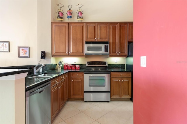 kitchen with light tile patterned flooring, appliances with stainless steel finishes, sink, and dark stone counters