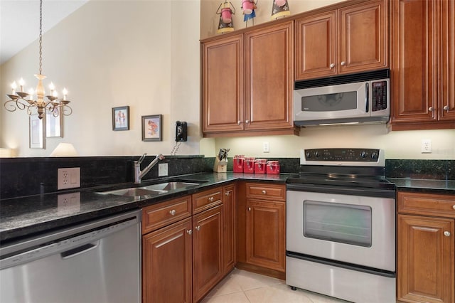 kitchen featuring stainless steel appliances, sink, dark stone countertops, and light tile patterned floors