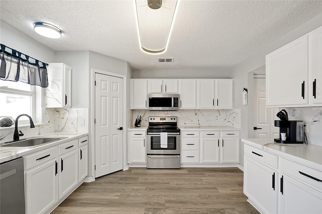 kitchen featuring sink, stainless steel appliances, tasteful backsplash, and white cabinetry