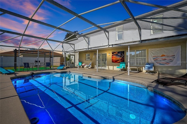 pool at dusk featuring a patio and glass enclosure