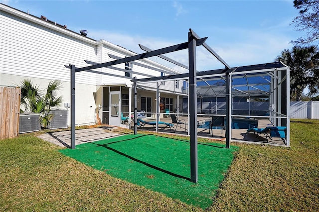 back of house featuring central air condition unit, a patio area, glass enclosure, and a lawn