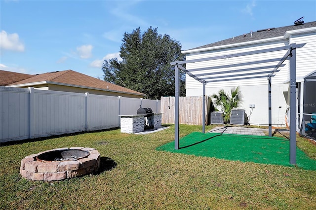 view of yard with a fire pit, cooling unit, and an outdoor kitchen