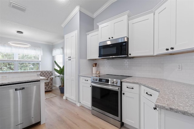 kitchen with light hardwood / wood-style floors, backsplash, appliances with stainless steel finishes, white cabinets, and crown molding