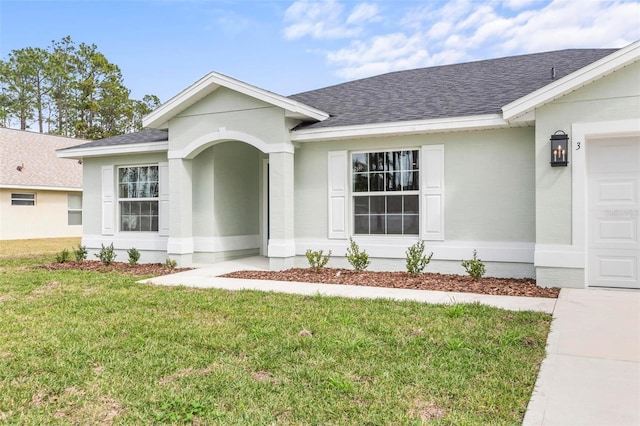 view of front facade with a front lawn, stucco siding, an attached garage, and a shingled roof