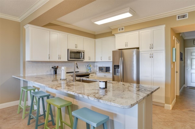 kitchen featuring stainless steel appliances, light stone countertops, kitchen peninsula, light tile patterned floors, and white cabinetry