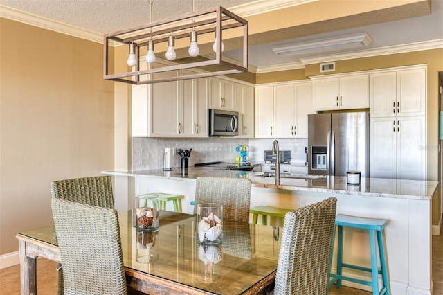 kitchen with tasteful backsplash, stainless steel appliances, white cabinetry, and light stone countertops