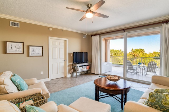 living room with ceiling fan, crown molding, light tile patterned flooring, and a textured ceiling