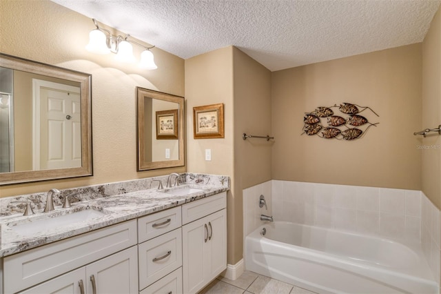 bathroom with tile patterned floors, vanity, a textured ceiling, and a bathing tub