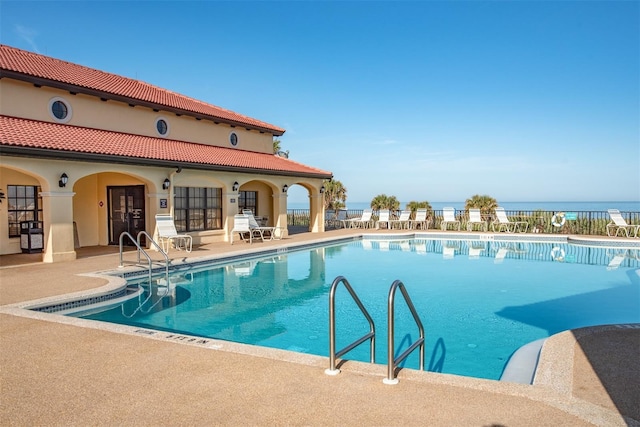 view of pool featuring a patio and a water view