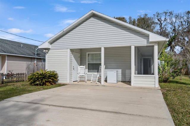 rear view of property featuring a lawn and covered porch