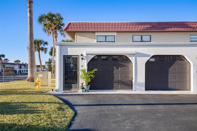 view of front of home featuring a garage, stucco siding, a front yard, and a tiled roof