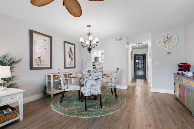 dining area featuring ceiling fan with notable chandelier and hardwood / wood-style floors