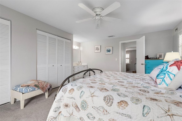 carpeted bedroom with ceiling fan and two closets