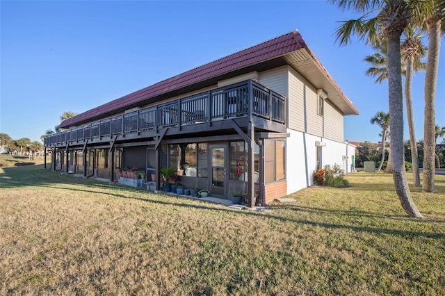 rear view of property featuring a lawn and a deck