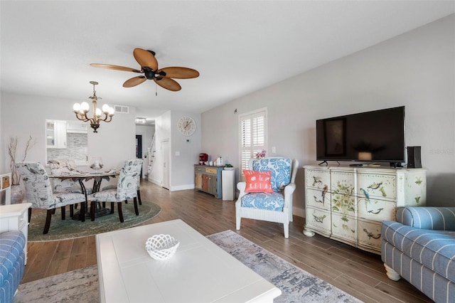 living area with baseboards, visible vents, wood finished floors, and ceiling fan with notable chandelier