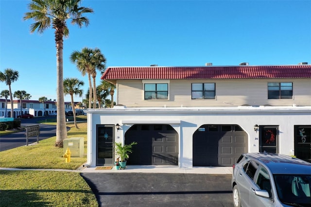 view of front of property with a garage, driveway, a tiled roof, and a front lawn