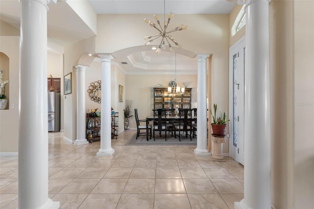 foyer featuring light tile patterned flooring, a chandelier, ornamental molding, and a tray ceiling