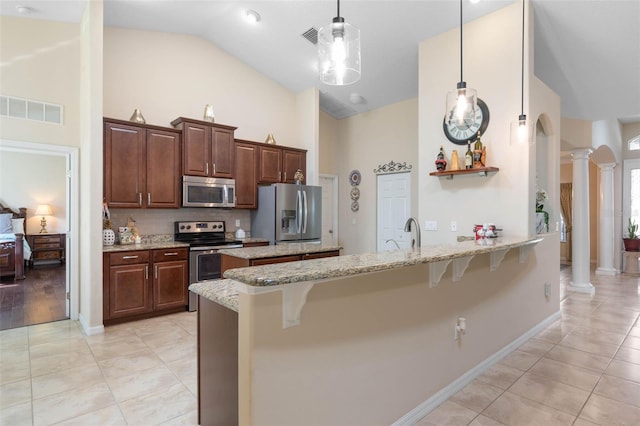 kitchen with a breakfast bar, pendant lighting, ornate columns, and stainless steel appliances