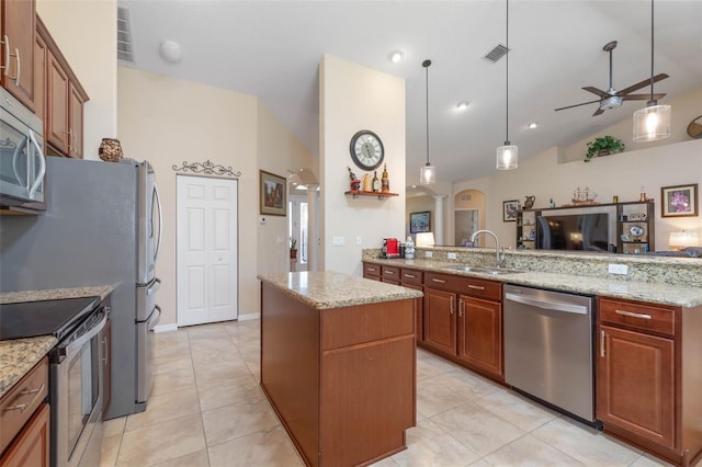 kitchen featuring appliances with stainless steel finishes, lofted ceiling, a kitchen island, hanging light fixtures, and light stone counters