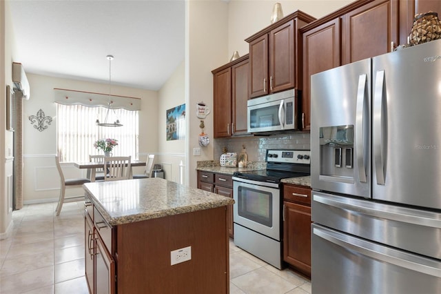 kitchen featuring stainless steel appliances, decorative light fixtures, light tile patterned flooring, light stone counters, and a center island