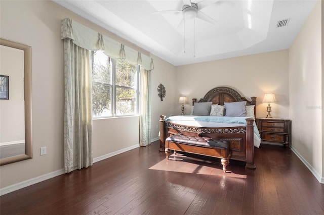 bedroom with ceiling fan, dark hardwood / wood-style flooring, and a raised ceiling