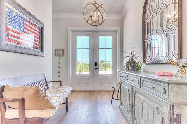 doorway featuring french doors, a notable chandelier, ornamental molding, and light hardwood / wood-style flooring