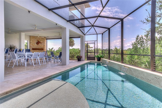 pool at dusk featuring ceiling fan, a fireplace, a patio area, pool water feature, and a lanai