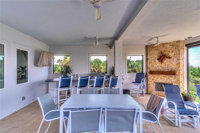 view of patio with ceiling fan and a stone fireplace