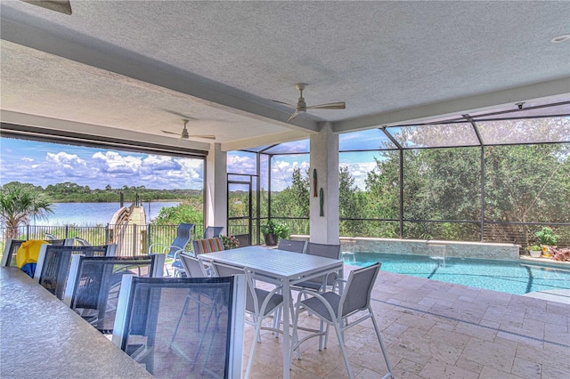 view of pool with ceiling fan, pool water feature, glass enclosure, a water view, and an outdoor bar