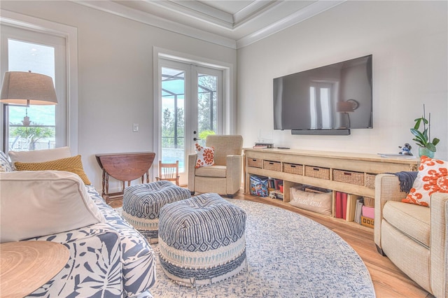 living area with light hardwood / wood-style flooring, crown molding, and french doors