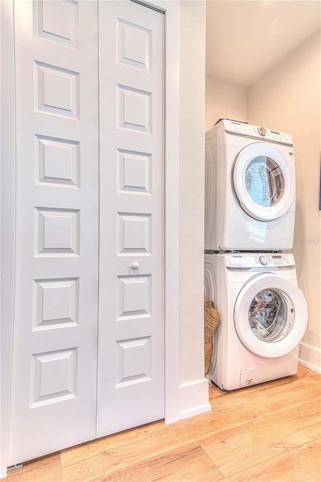 clothes washing area featuring stacked washer and dryer and light hardwood / wood-style flooring