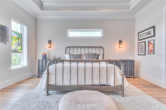 bedroom featuring a tray ceiling, light hardwood / wood-style flooring, and crown molding