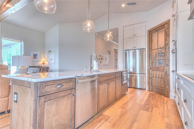 kitchen featuring stainless steel appliances, a kitchen island with sink, hanging light fixtures, white cabinets, and sink