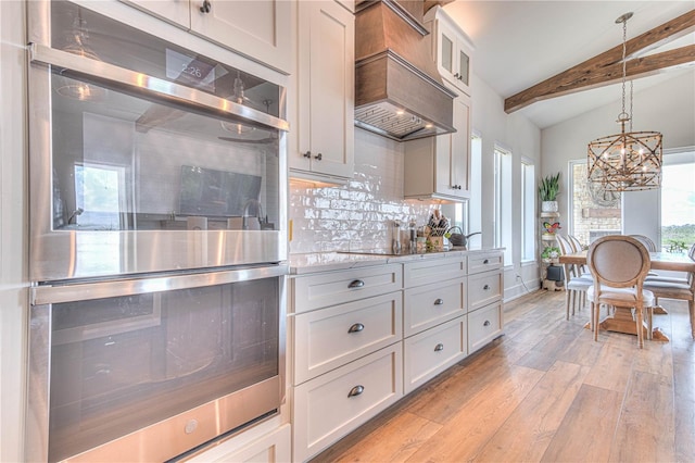 kitchen featuring decorative light fixtures, tasteful backsplash, white cabinetry, light wood-type flooring, and double oven