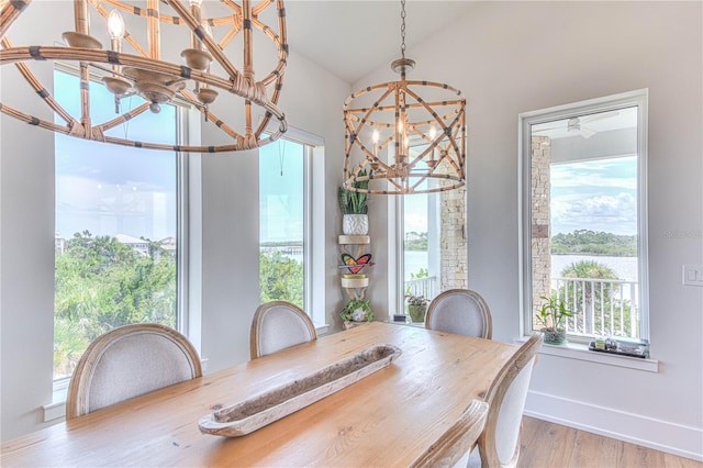 dining area with light wood-type flooring, a chandelier, and vaulted ceiling