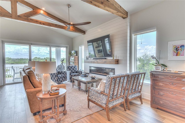 living room featuring ceiling fan, light hardwood / wood-style flooring, and lofted ceiling with beams