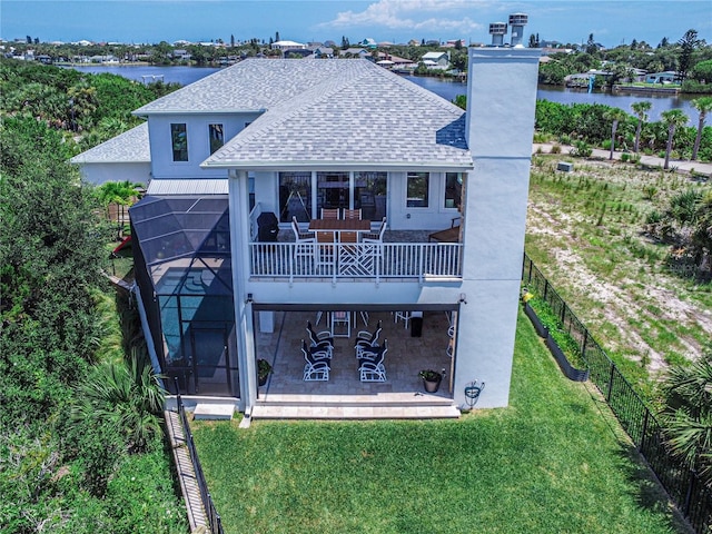 rear view of house featuring a lanai, a water view, a lawn, and a patio