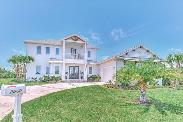 view of front of house featuring a front lawn, french doors, a balcony, and a garage