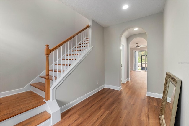 stairway featuring ceiling fan and hardwood / wood-style floors