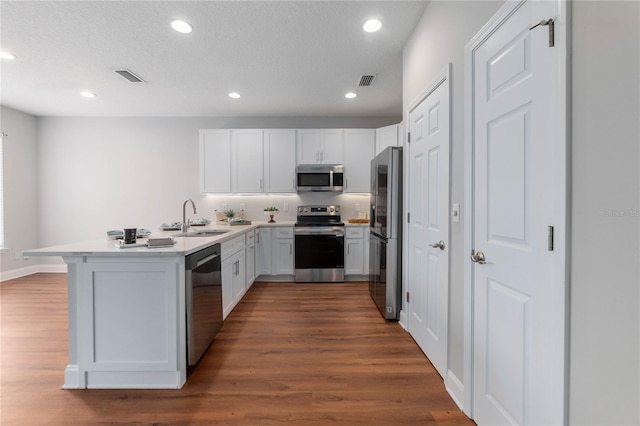 kitchen featuring white cabinetry, dark hardwood / wood-style flooring, stainless steel appliances, sink, and kitchen peninsula