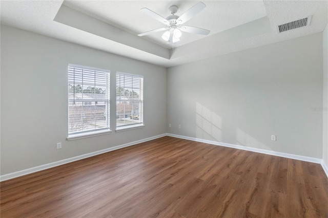 unfurnished room featuring hardwood / wood-style flooring, a tray ceiling, and ceiling fan