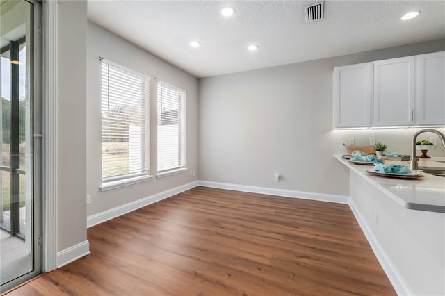 unfurnished dining area featuring dark hardwood / wood-style flooring, sink, and a textured ceiling