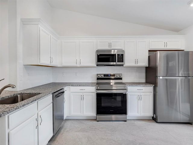 kitchen with vaulted ceiling, stainless steel appliances, white cabinetry, and sink