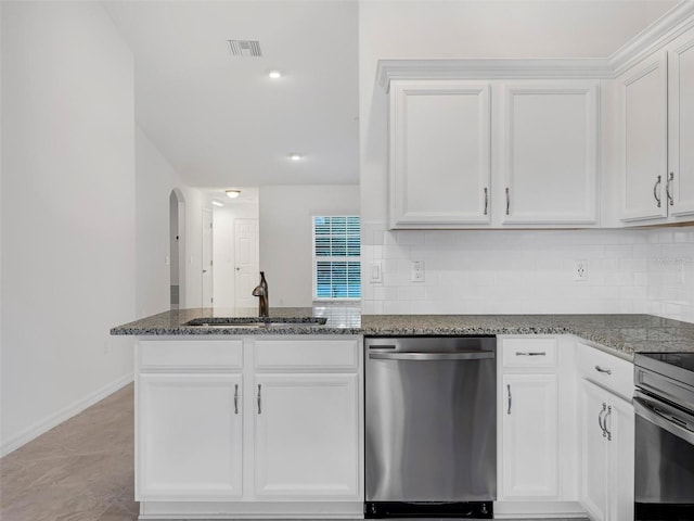 kitchen featuring white cabinets, dishwasher, range, dark stone countertops, and decorative backsplash