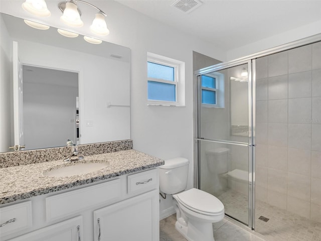 bathroom featuring toilet, vanity, tile patterned flooring, and a shower with door