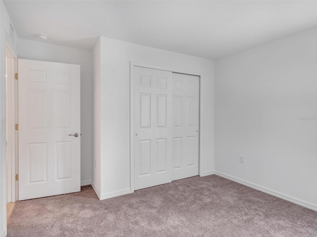 unfurnished bedroom with light carpet and a closet