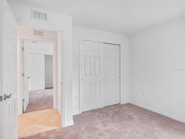 unfurnished bedroom featuring a closet and light colored carpet