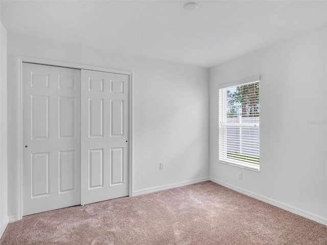 unfurnished bedroom with light carpet and a closet