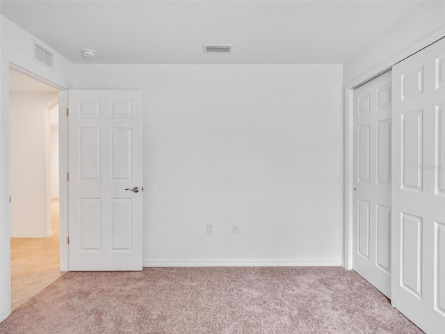 unfurnished bedroom featuring light carpet and a closet